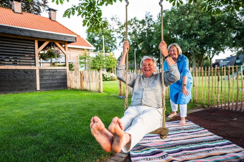 Lachende man op schommel in een tuin met graszoden