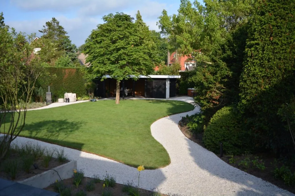 Achtertuin met strak gelegde graszoden en sierbestrating bij een veranda