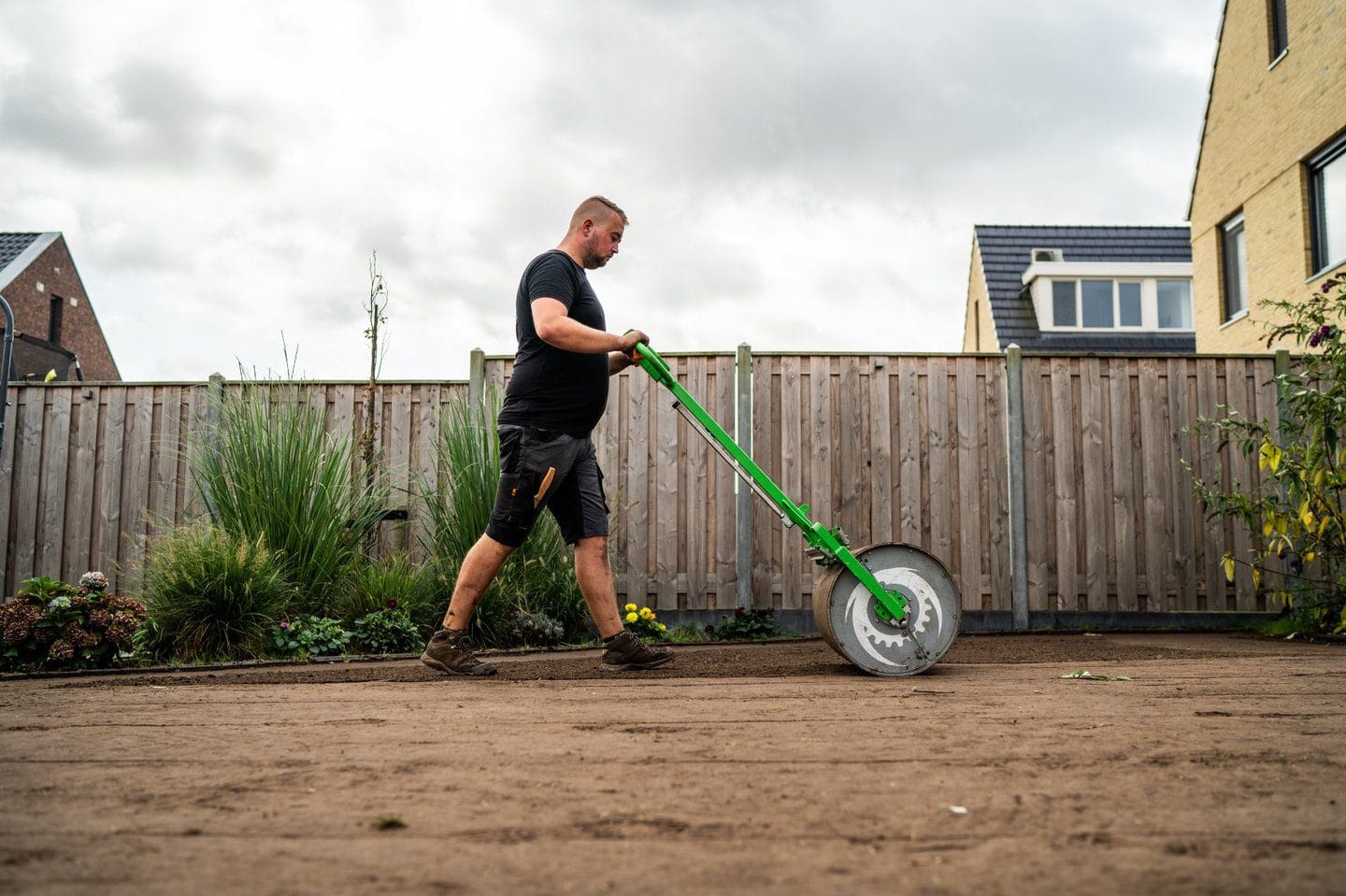 Hovenier walst geëgaliseerde zandgrond aan als voorbereiding op het leggen van graszoden