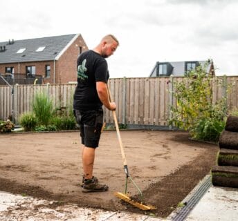 Medewerker egaliseert de ondergrond zorgvuldig ter voorbereiding op het leggen van graszoden.