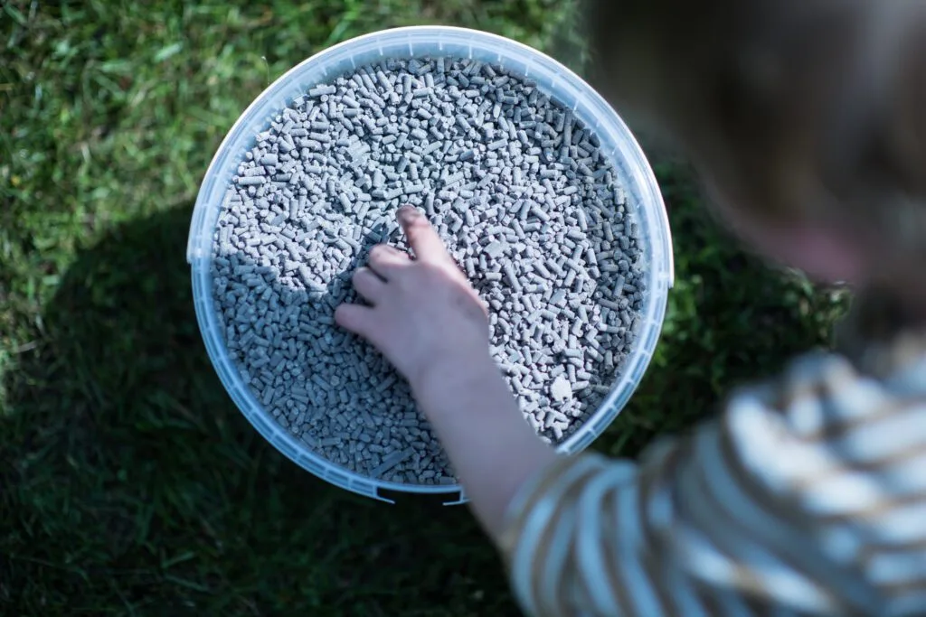 Kind pakt bemestingskorrels uit een bak voor het gazon