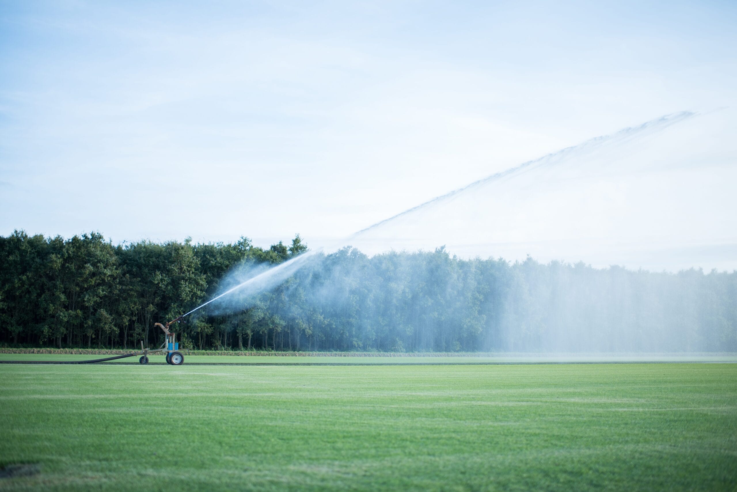 Beregeningshaspel sproeit water over een groot graszodenveld