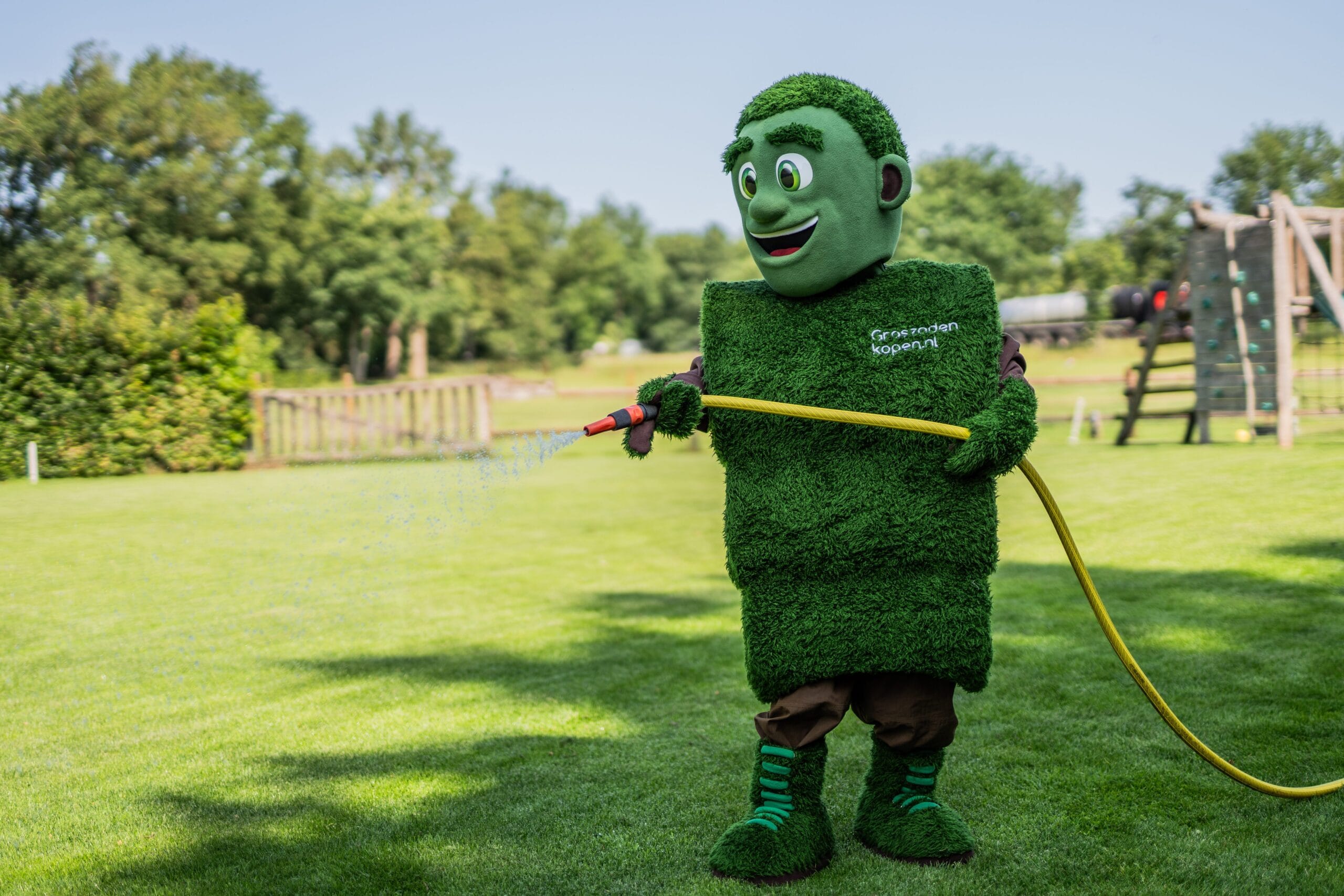 Grasmattie sproeit een vers groen gazon om het gras goed te laten wortelen na de aanleg.