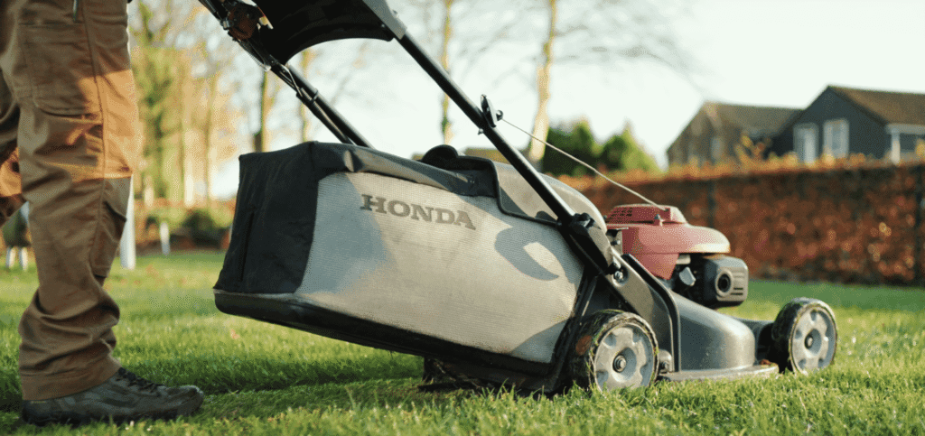 Honda grasmaaier met opvangbak tijdens het maaien van het gazon, duidelijk voorbeeld van maaien zonder mulchen.