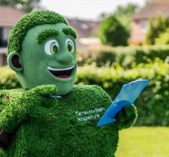 Mascotte Grasmattie met clipboard geeft tips voor het leggen van graszoden
