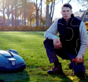 Een gazon in het voorjaar met een robotmaaier waarbij uitleg wordt gegeven door een hovenier