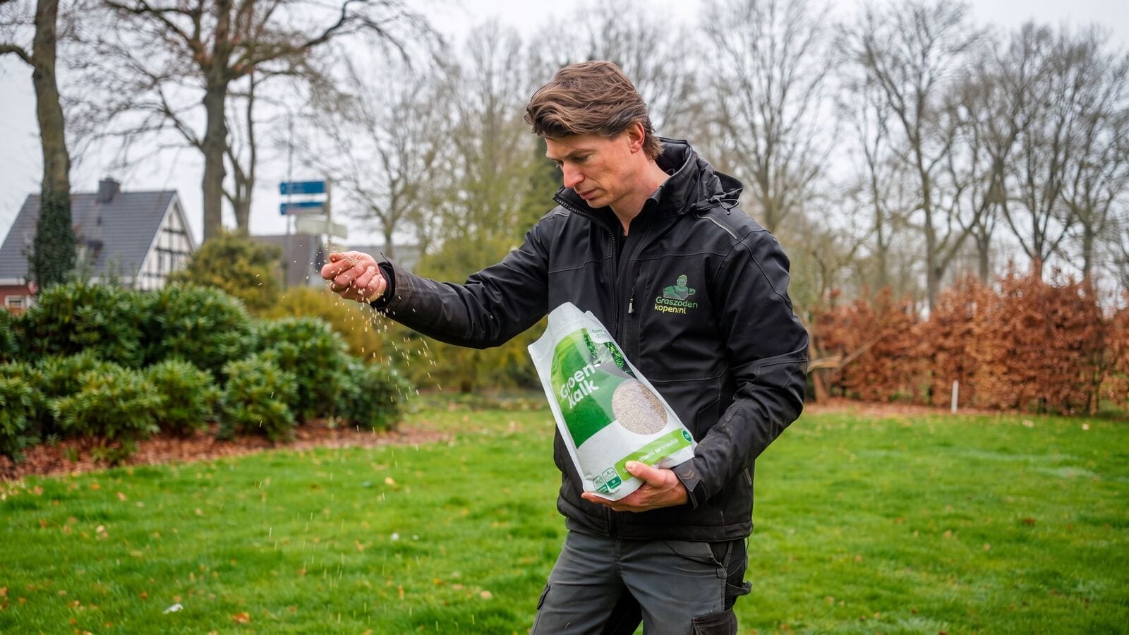 Hovenier strooit aanlegbemesting handmatig over het gazon